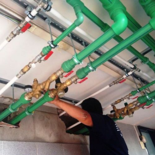 Imagen de operario manipulando tubos de fontanería en techo
